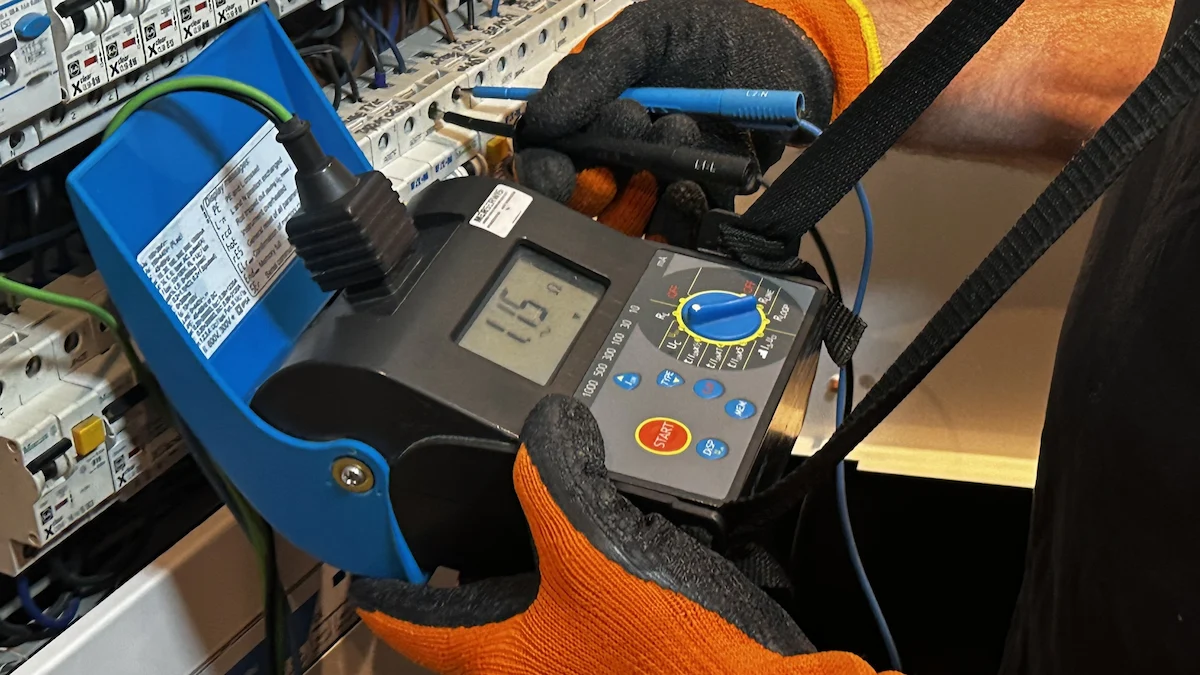 Elektryk wykonuje pomiary elektryczne rozdzielnicy w Warszawie za pomocą profesjonalnego miernika parametrów instalacji.