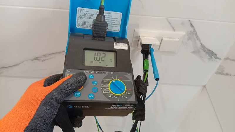 Elektryk wykonuje pomiar instalacji elektrycznej w gnieździe po remoncie mieszkania.